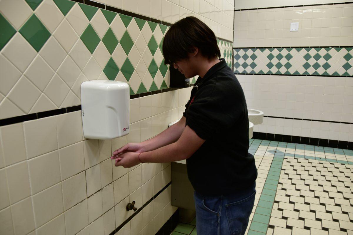 Vincent Melgazo (12) using the air dryer in a student bathroom