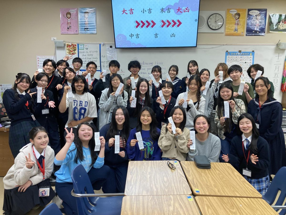 Mills students and the Japanese exchange students pose for a photo while holding omikuji (good fortune paper slips).