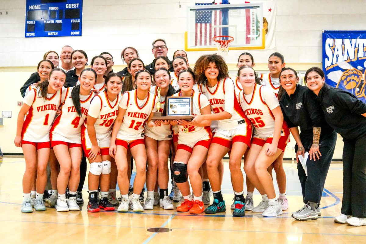 Girls basketball takes a team photo holding the championship trophy 